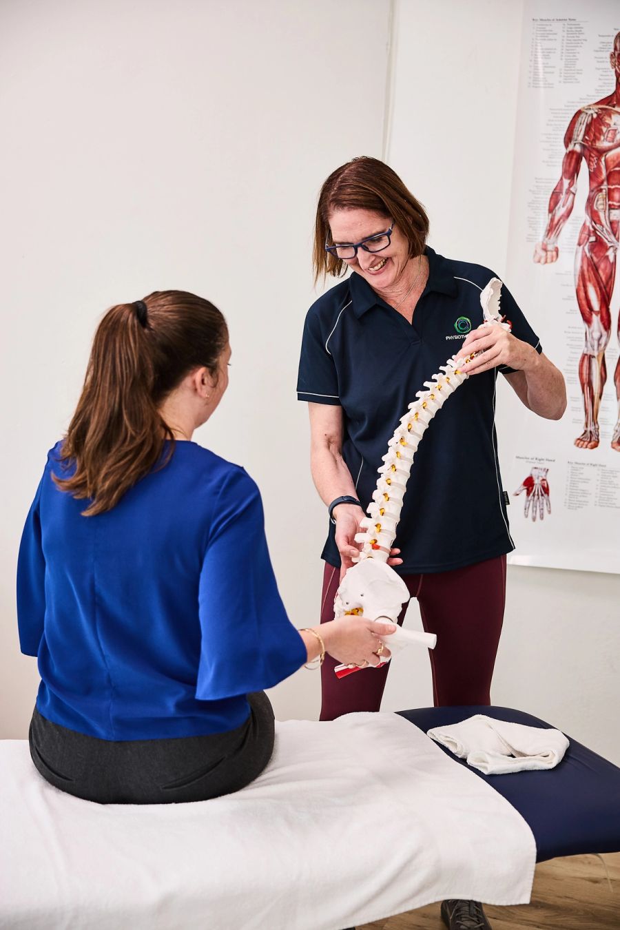 Physiotherapist explaining spine movement to a patient using a model