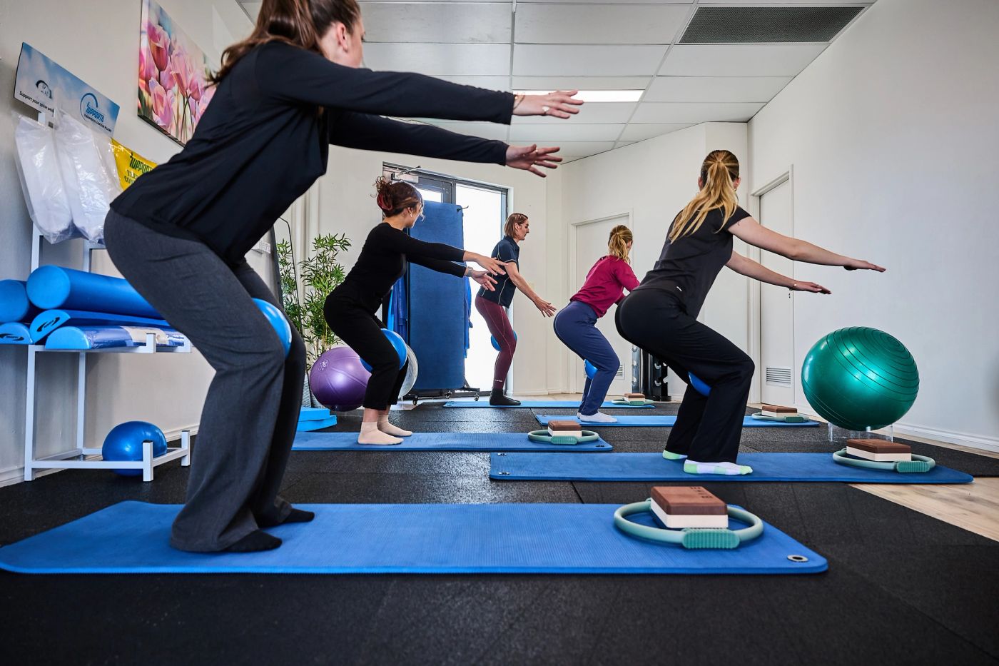 Small group class doing squats on mats in the clinic studio