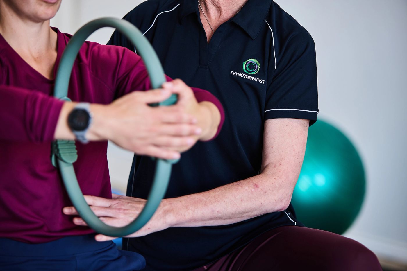 Physiotherapist guiding a client’s arms through a Pilates ring exercise