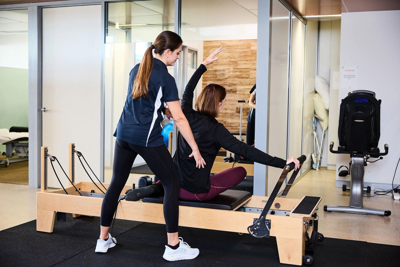 Bright Pilates studio with a physiotherapist guiding a client on the reformer