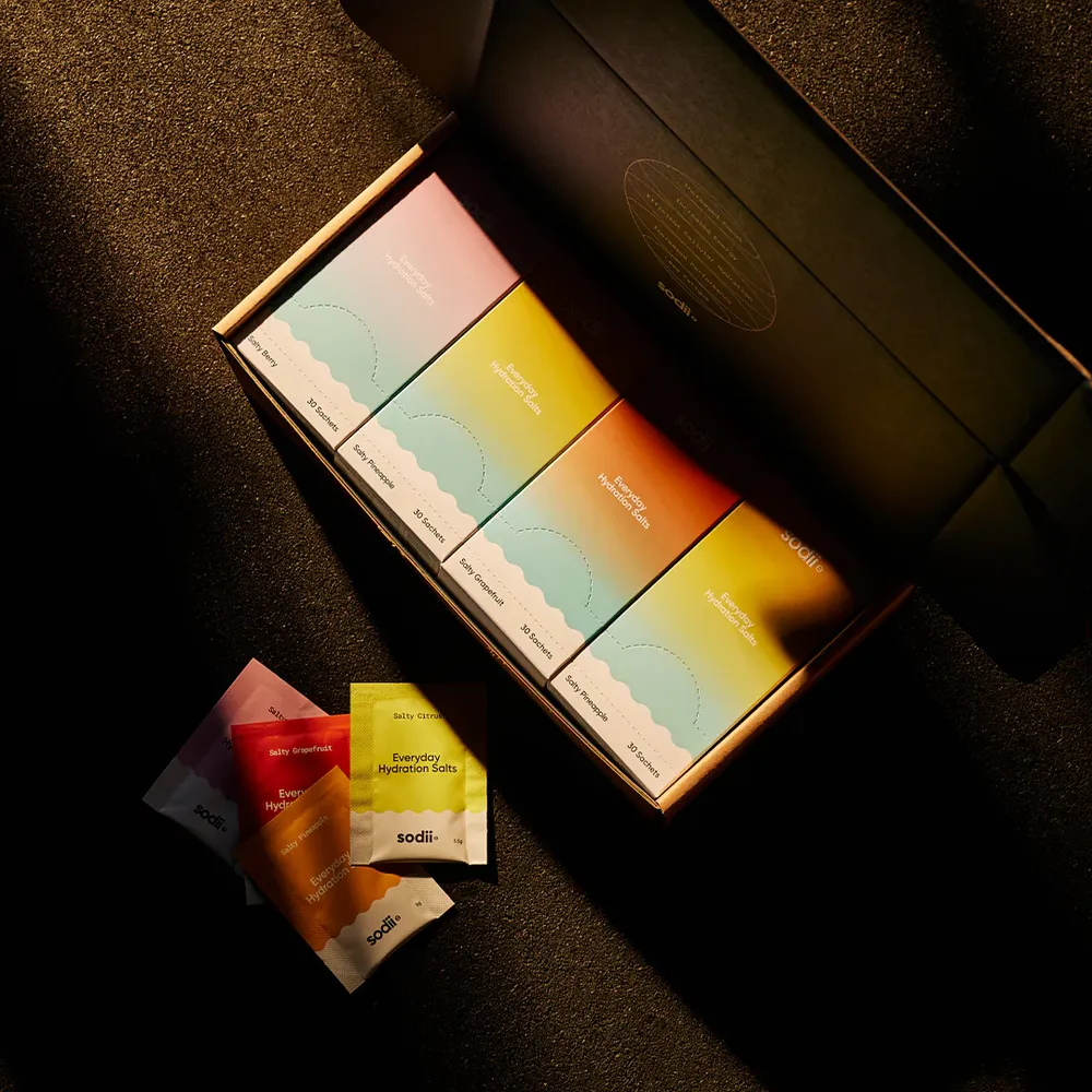 Sodii electrolyte hydration sachets in colourful packaging displayed in premium gift box set on dark textured surface