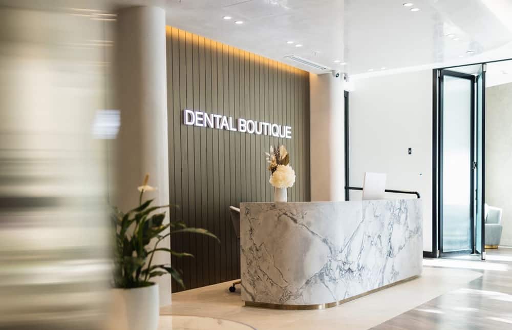Modern reception area of Dental Boutique with a marble front desk, neutral interiors, and minimalist décor.