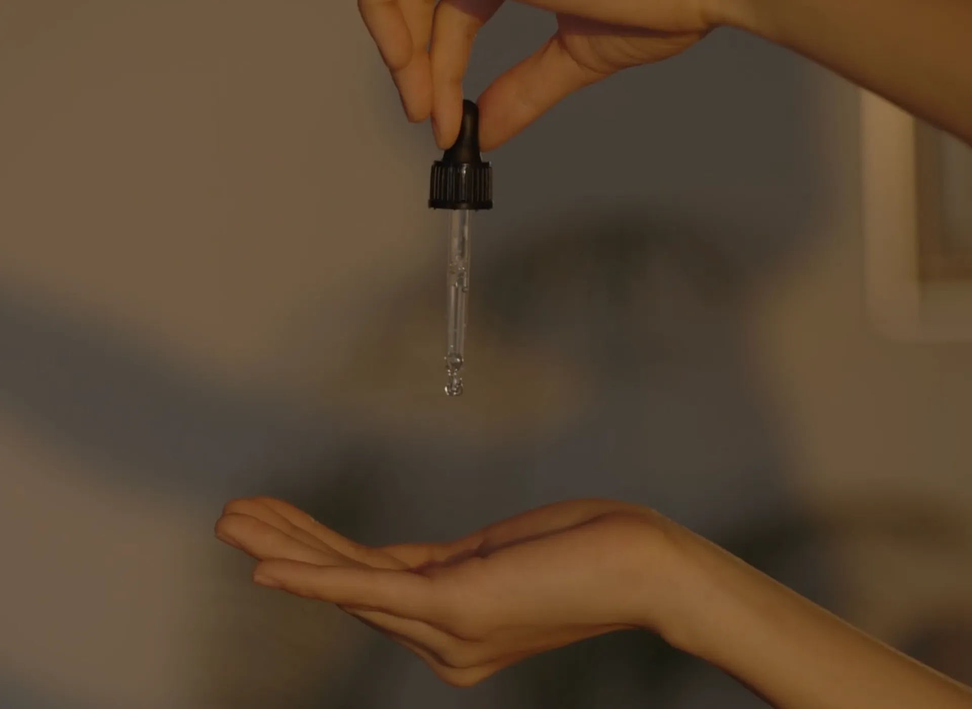 Hand holding skincare dropper releasing serum into palm