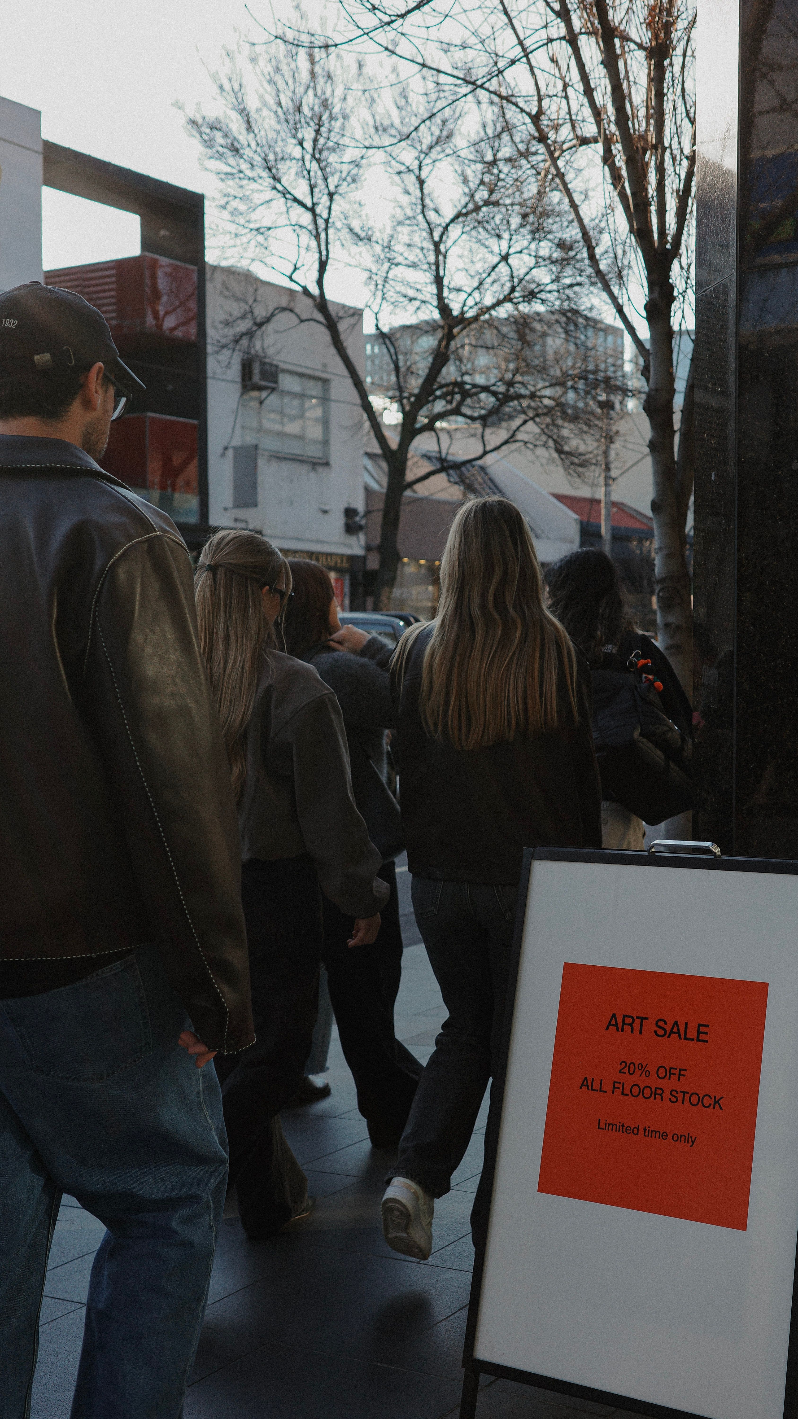 House of Psalm team walking through Melbourne city past art sale sign during culture day outing