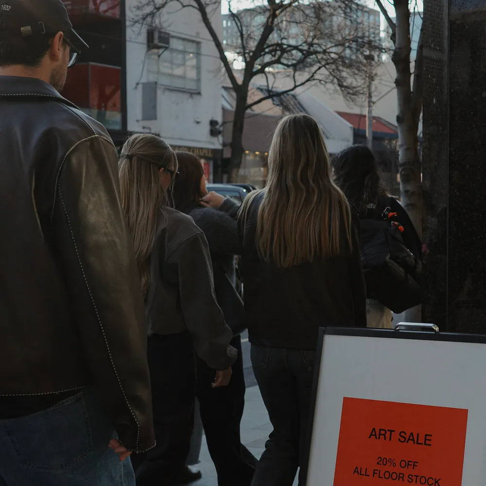 House of Psalm team walking through Melbourne city past art sale sign during culture day outing
