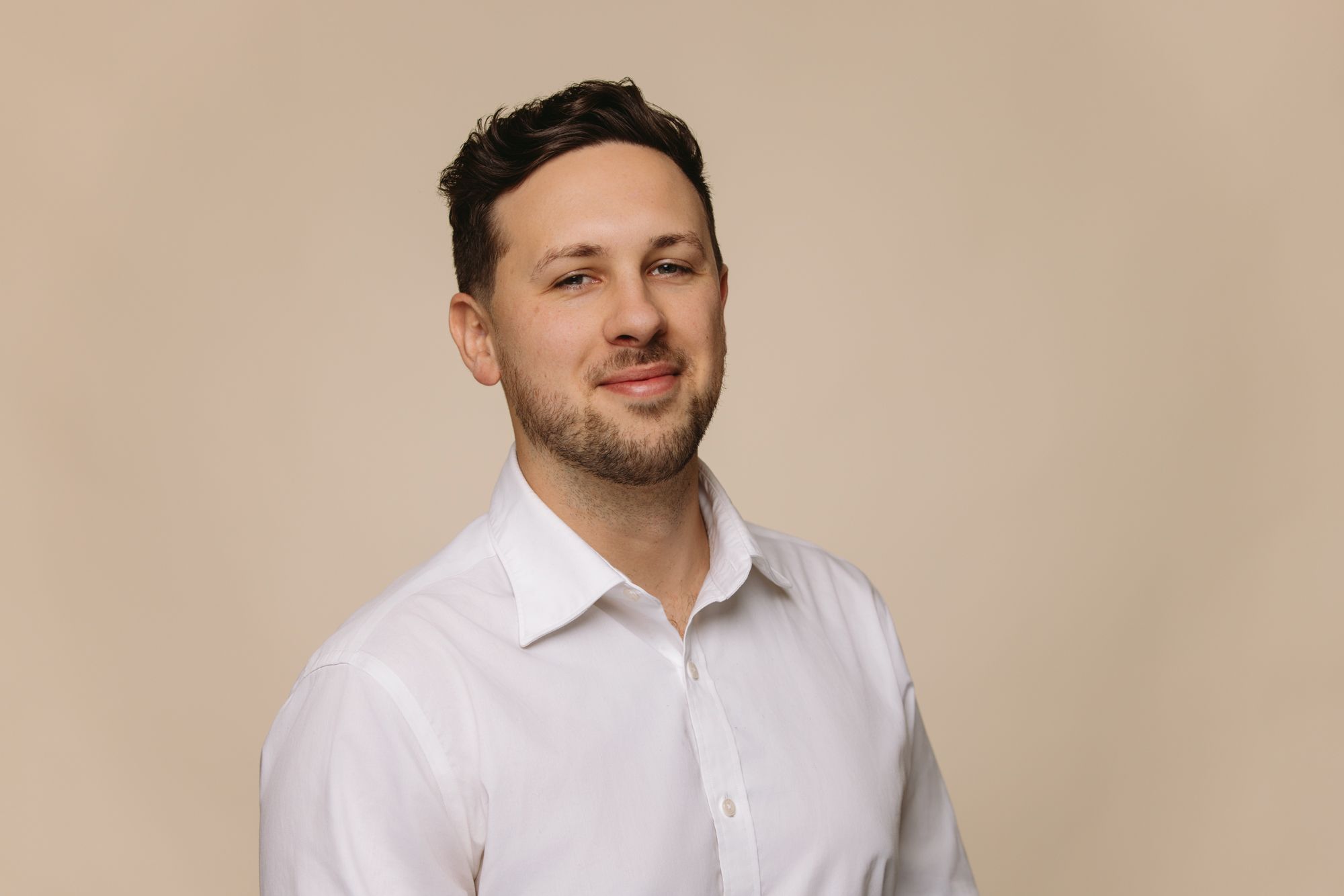 Jacob King Stanley Director of House of Psalm professional headshot wearing white shirt and tan jacket