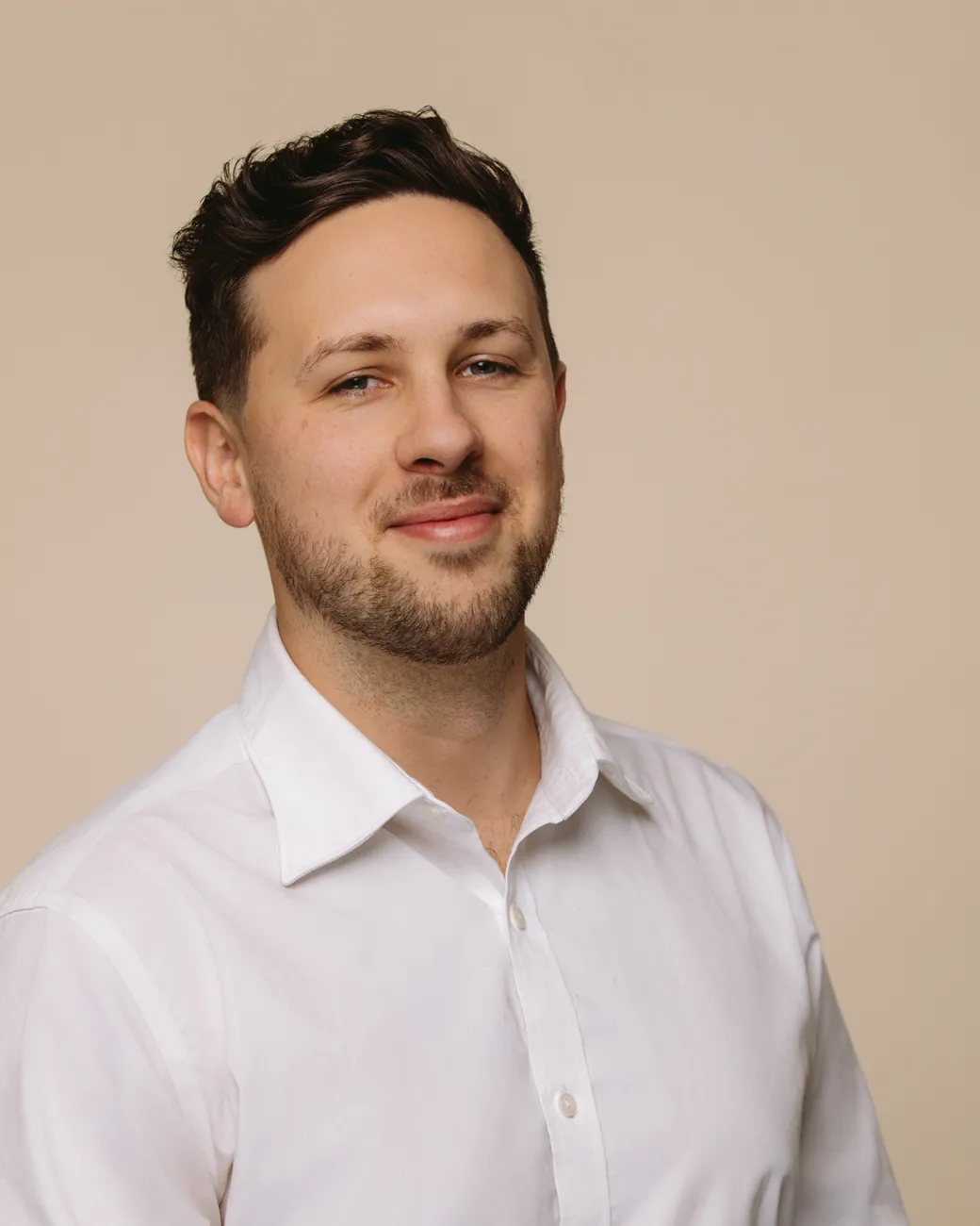 Jacob King Stanley Director of House of Psalm professional headshot wearing white shirt and tan jacket