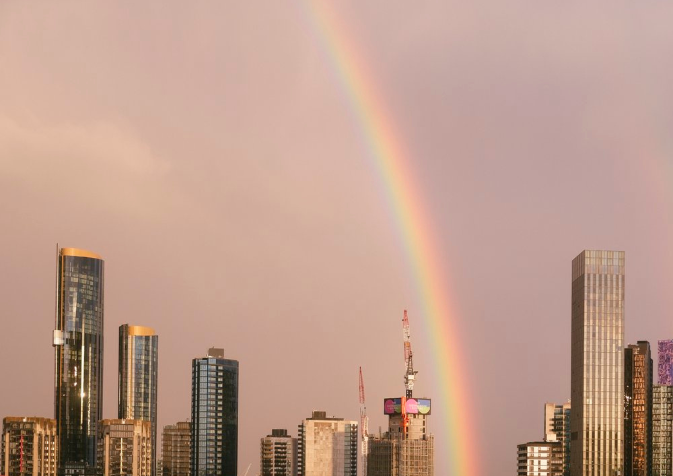 Rainbow over Melbourne city skyline at sunset