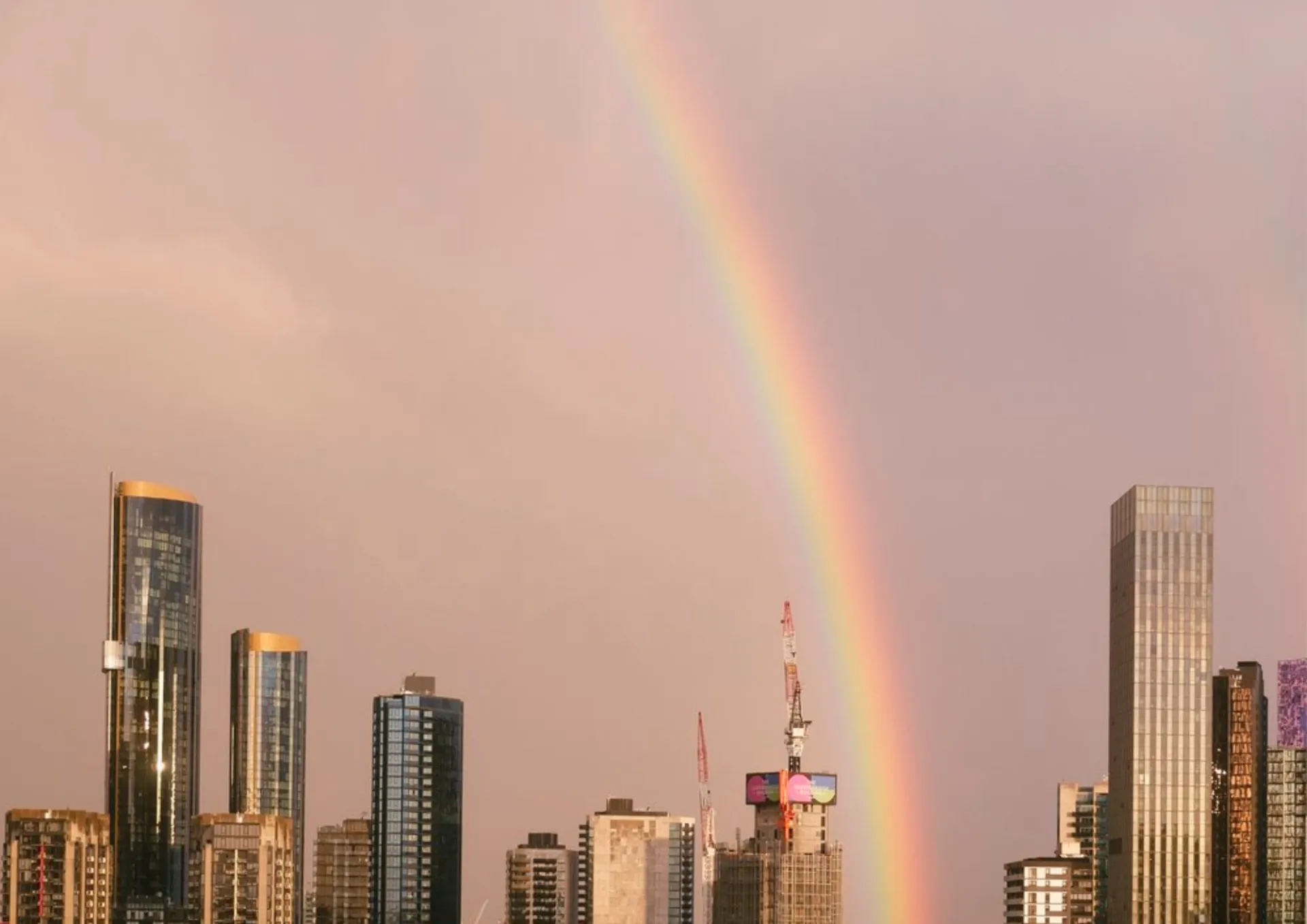 Rainbow over Melbourne city skyline at sunset