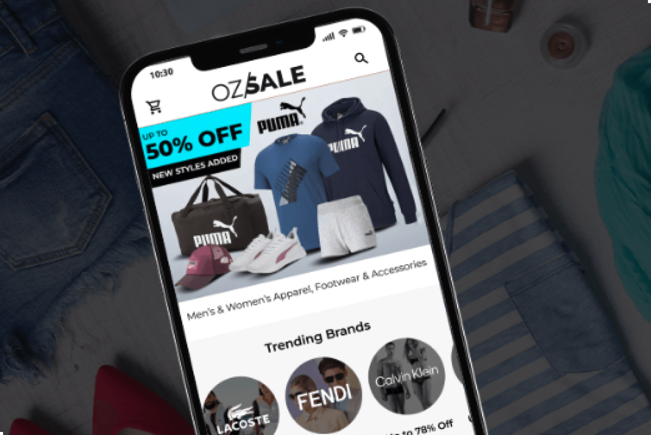 OzSale mobile app open on a smartphone screen, showing Puma apparel and accessories promotion with trending brands like Lacoste, Fendi, and Calvin Klein.