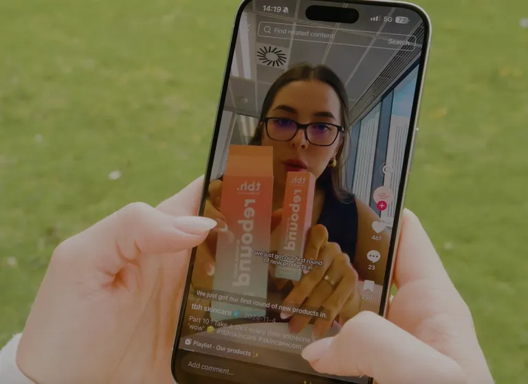 Person holding phone showing TBH Skincare TikTok video about new product launch