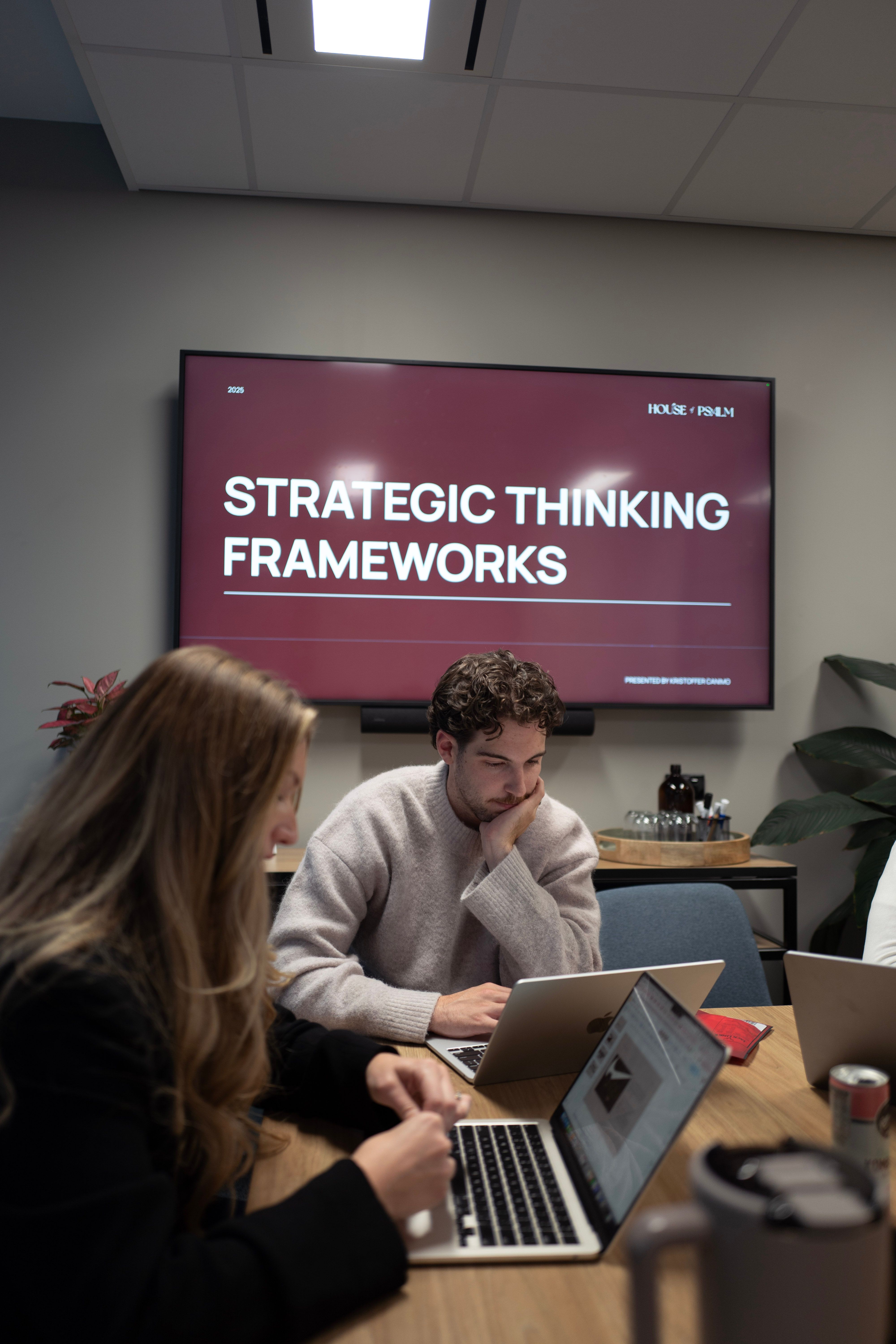 House of Psalm team in strategy workshop with laptops discussing Strategic Thinking Frameworks presentation in office
