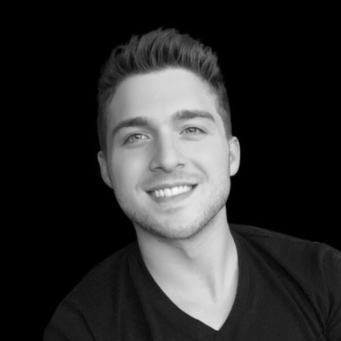 Jake Dimarco from Venue Now professional headshot in black t-shirt smiling against dark background