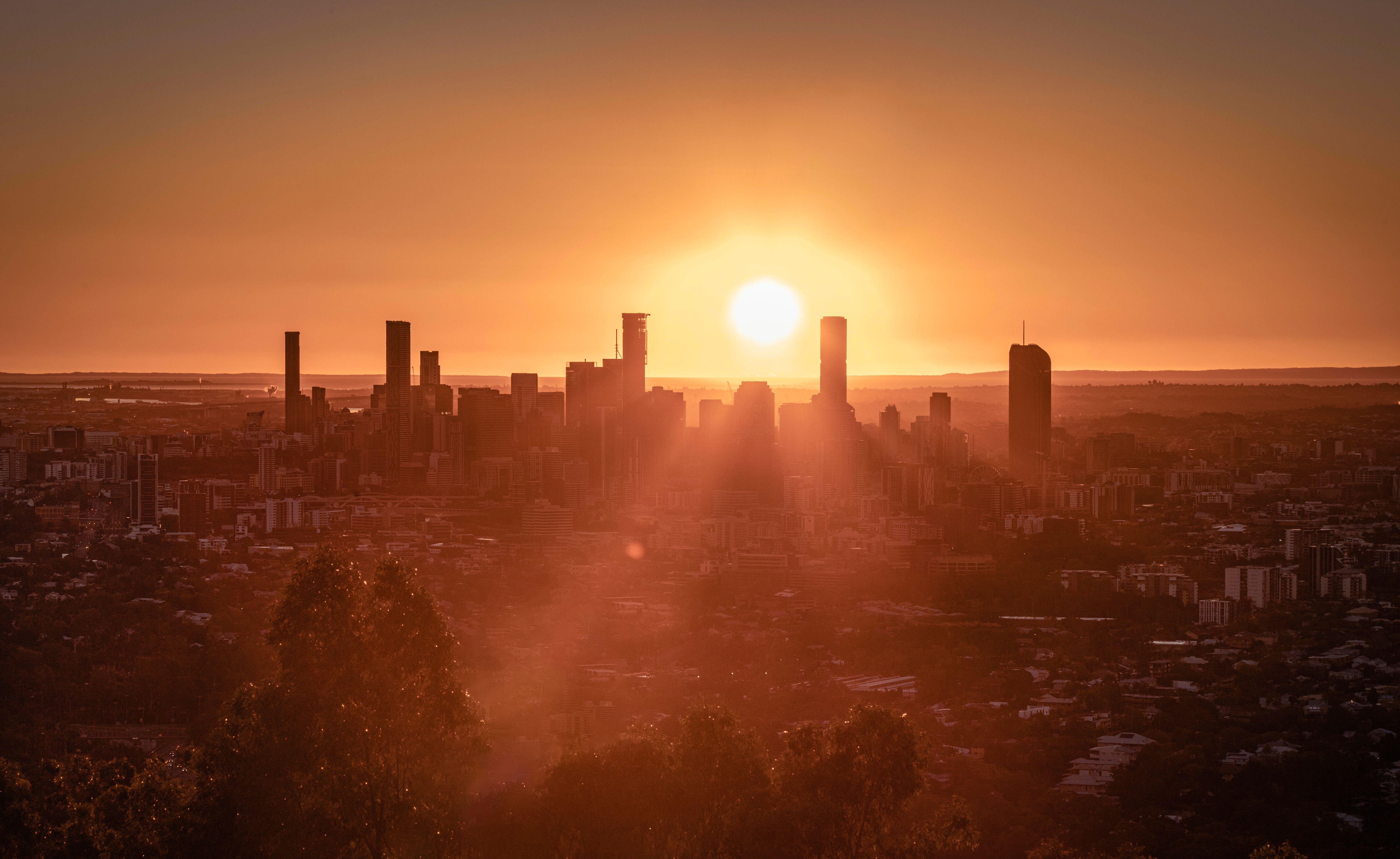 Sunset over Brisbane city skyline with glowing orange sky and silhouetted skyscrapers