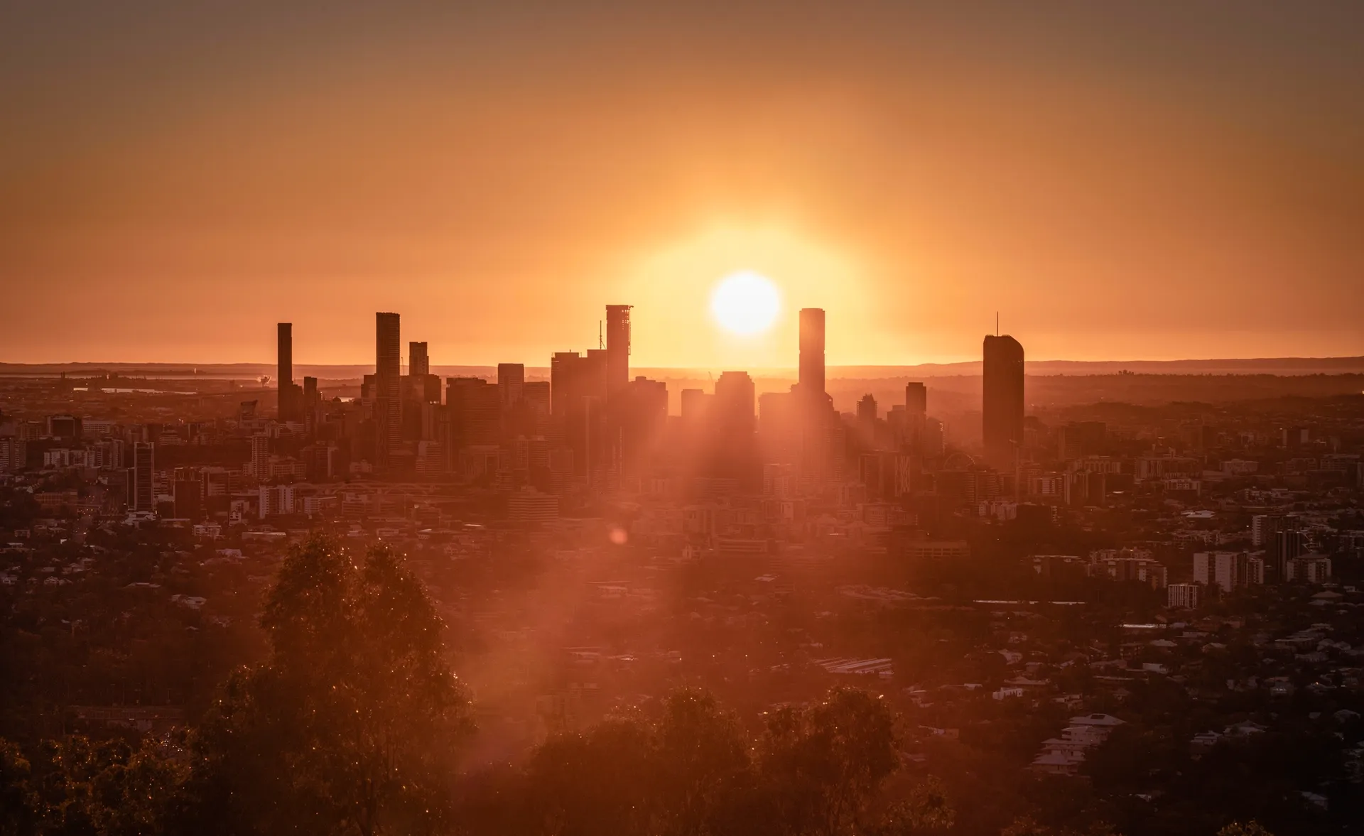 Sunset over Brisbane city skyline with glowing orange sky and silhouetted skyscrapers