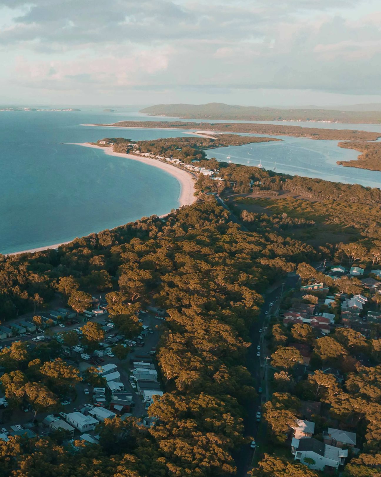 Aerial view of Reflections Holidays park on the NSW coast, surrounded by lush trees and overlooking the ocean