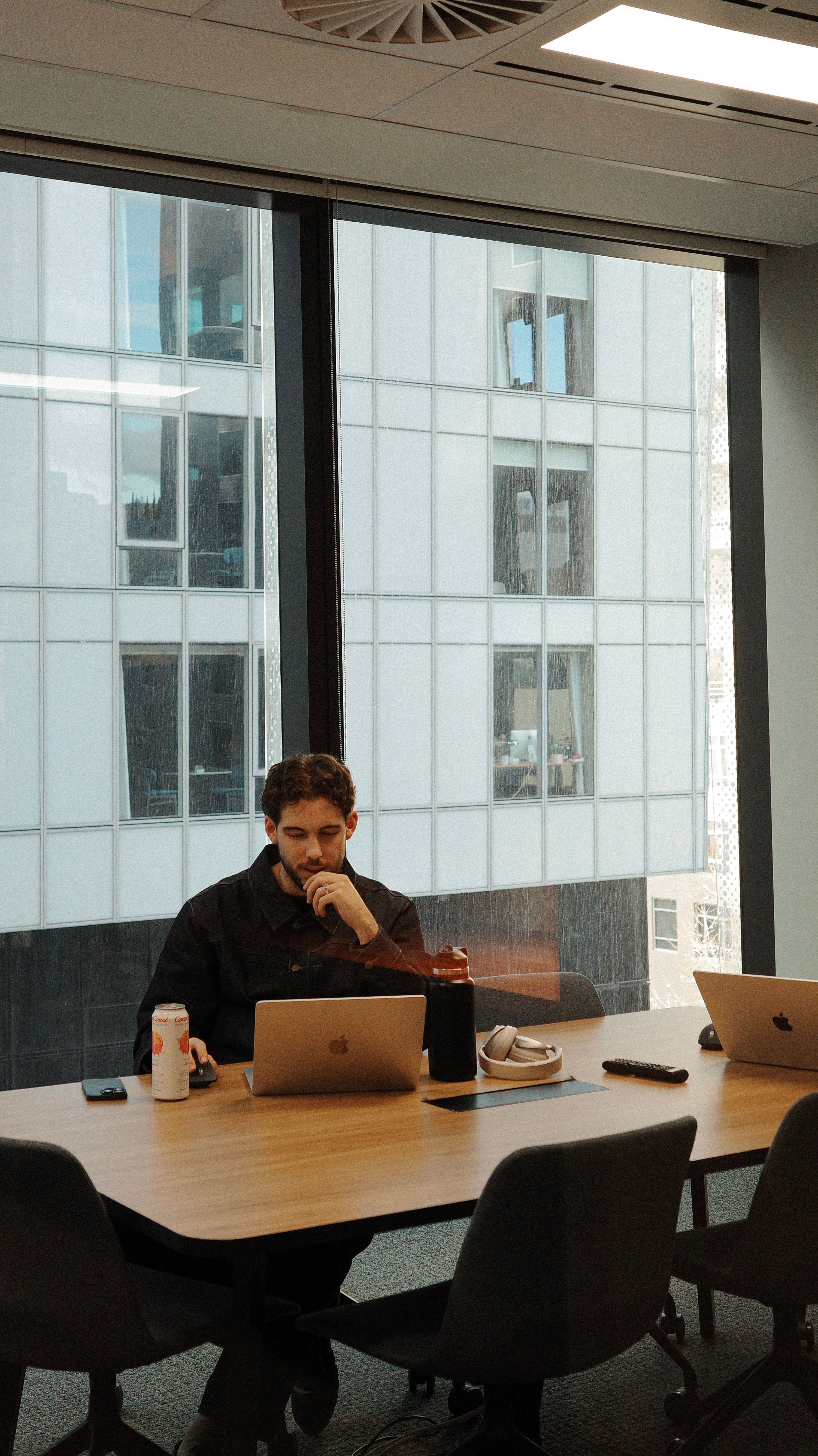 House of Psalm team member working on laptop with multiple devices in modern office meeting room