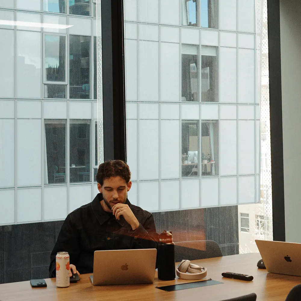 House of Psalm team member working on laptop with multiple devices in modern office meeting room