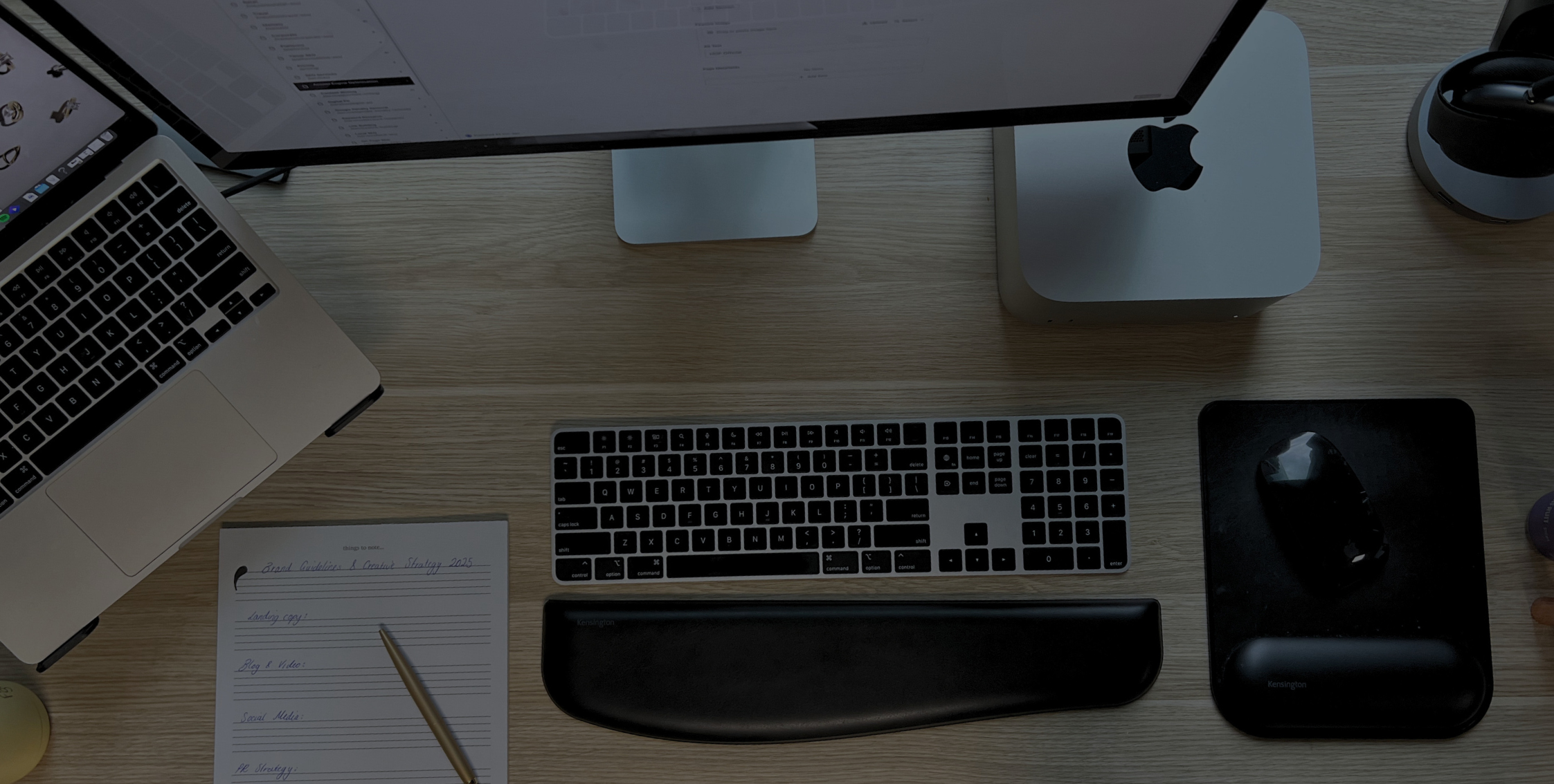 Modern work desk setup with Apple MacBook, iMac, keyboard, and notepad, representing House of Psalm’s digital workspace for SEO and creative strategy.