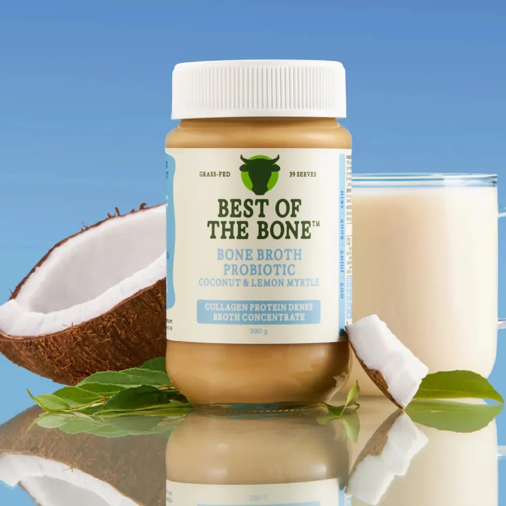 Best of the Bone coconut and lemon myrtle bone broth probiotic jar with coconut, bay leaves and a glass of broth against a blue background.