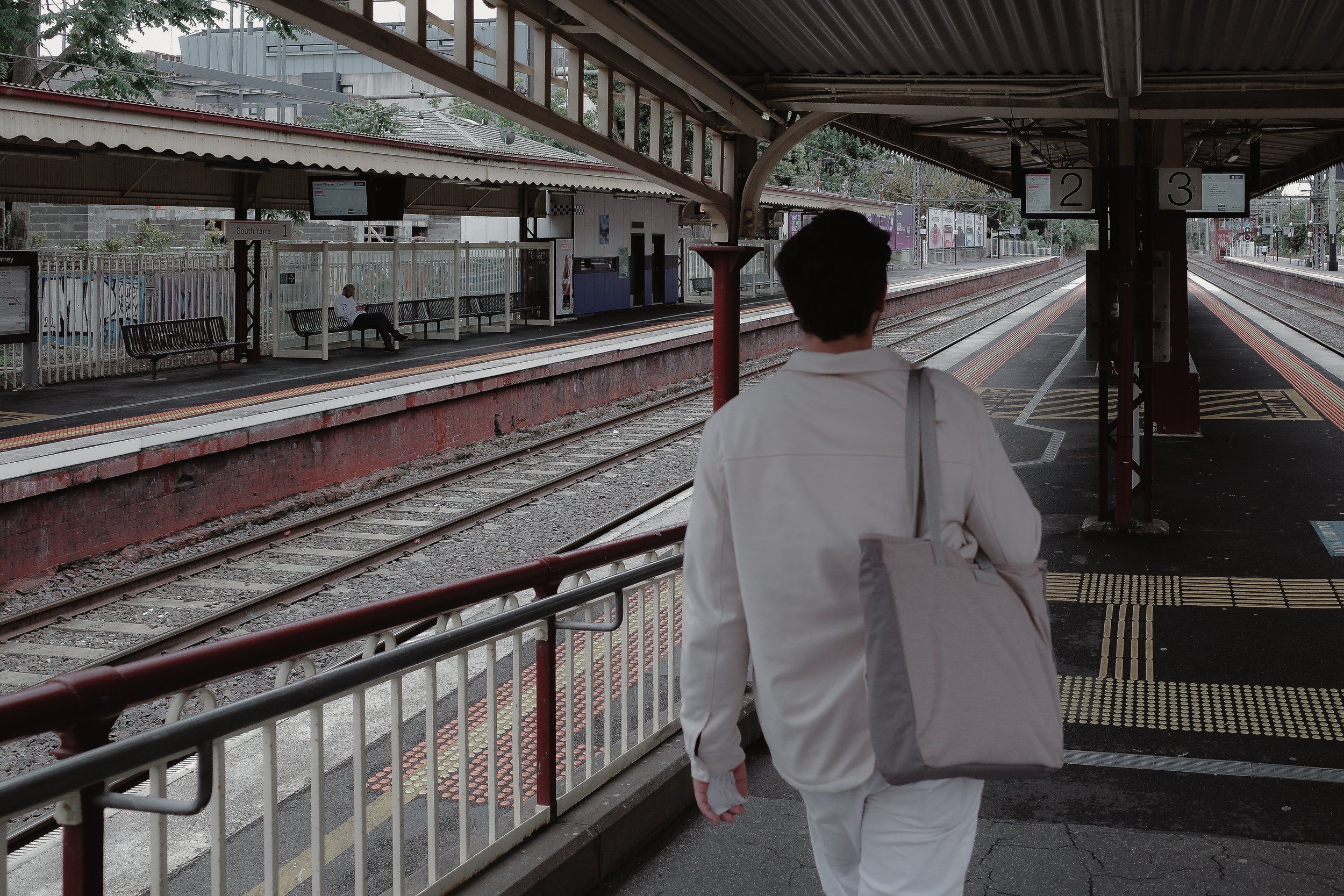House of Psalm team member on the way to work standing at Melbourne train platform with tote bag