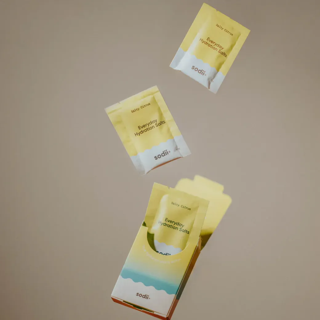 Sodii Everyday Hydration Sachets in yellow packaging, displayed mid-air above the product box.