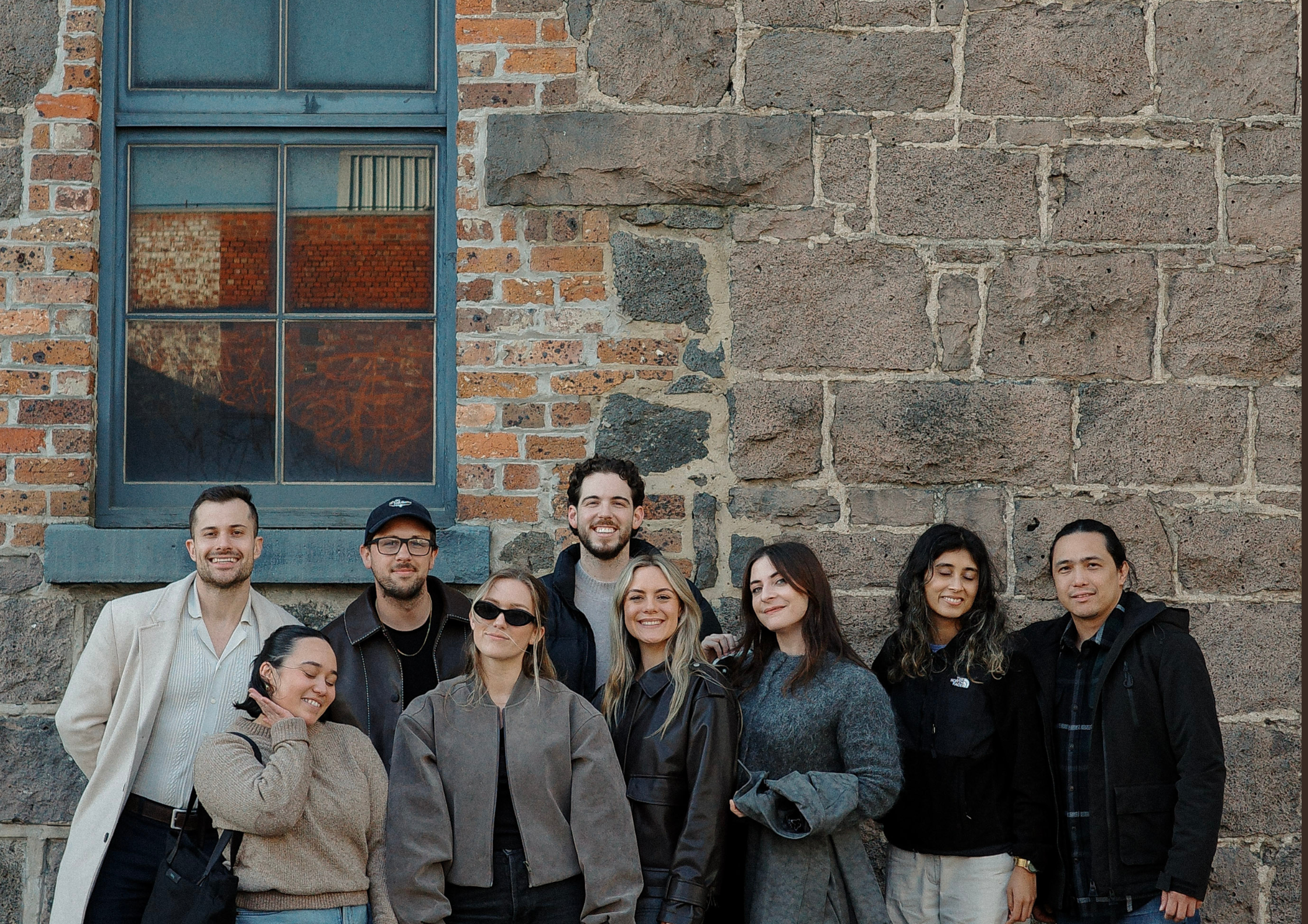 House of Psalm team group photo standing together in front of rustic brick wall in Melbourne