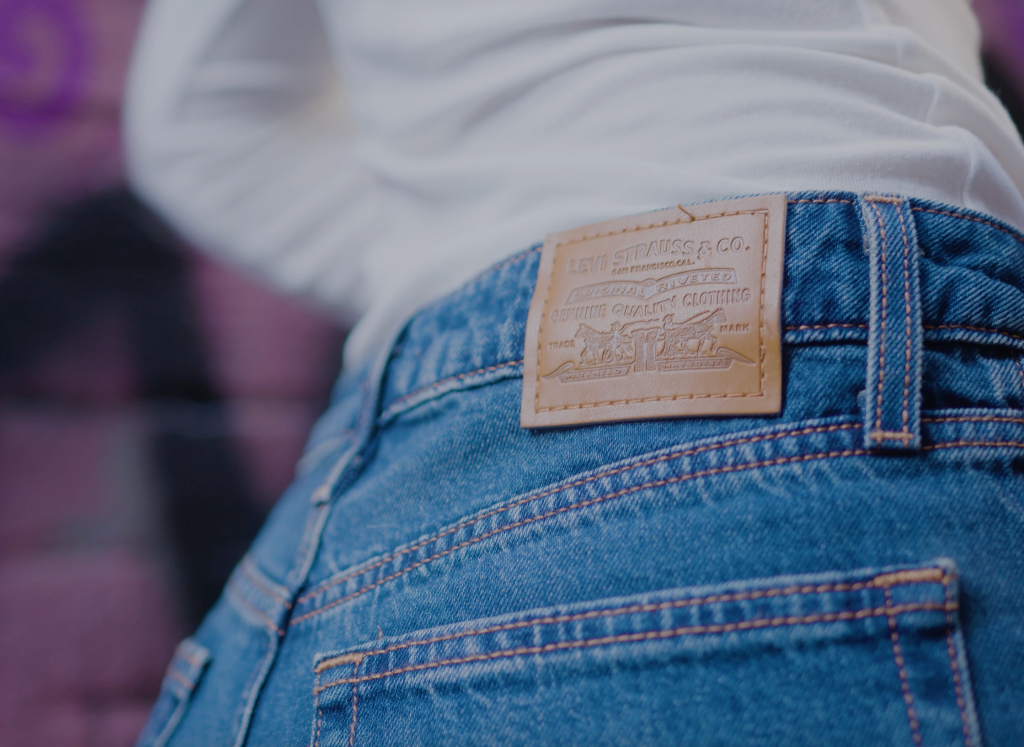 Back view of Levi’s Strauss & Co. classic blue denim jeans with brown leather patch branding, styled with a white top.