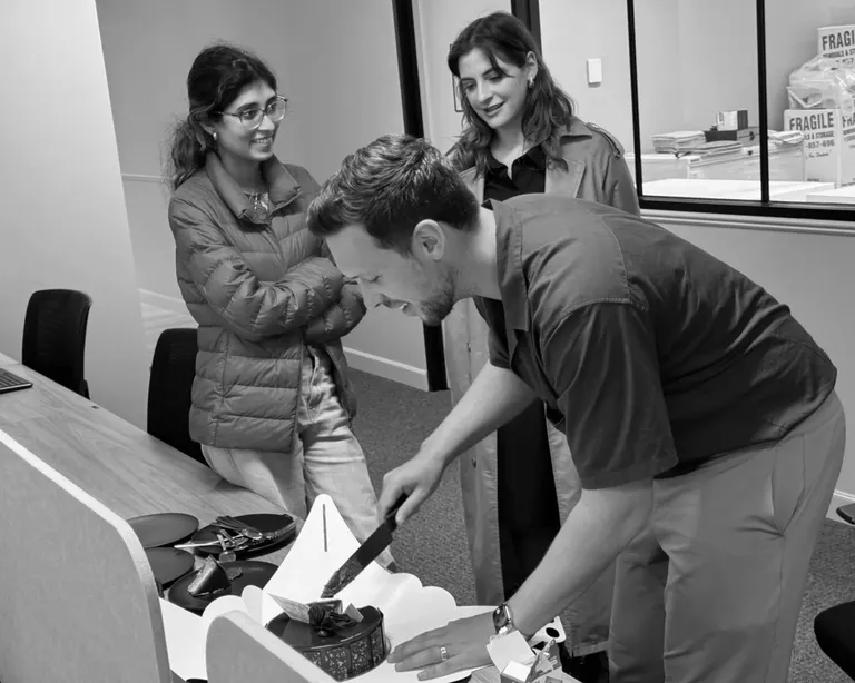 House of Psalm team celebrating in office with cake cutting and colleagues watching