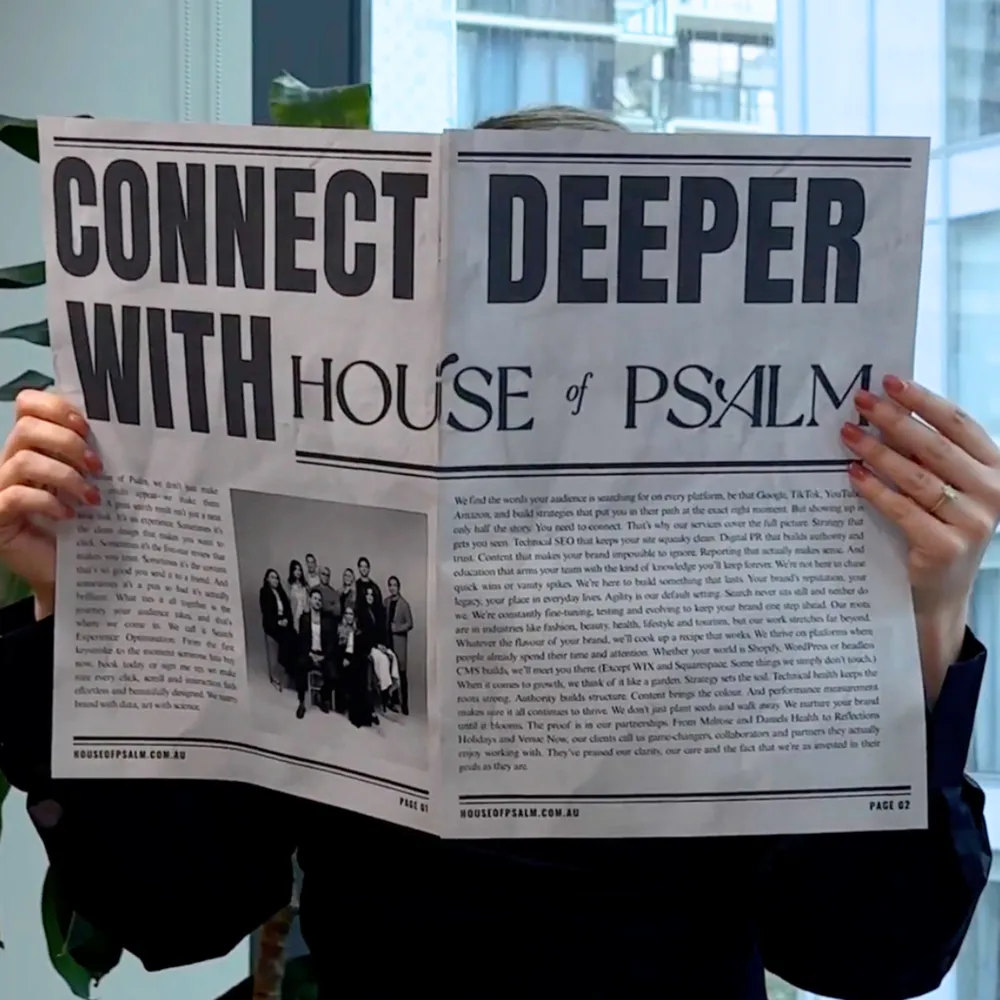Person holding a newspaper with the headline “Connect Deeper with House of Psalm,” featuring agency branding and team photo inside.