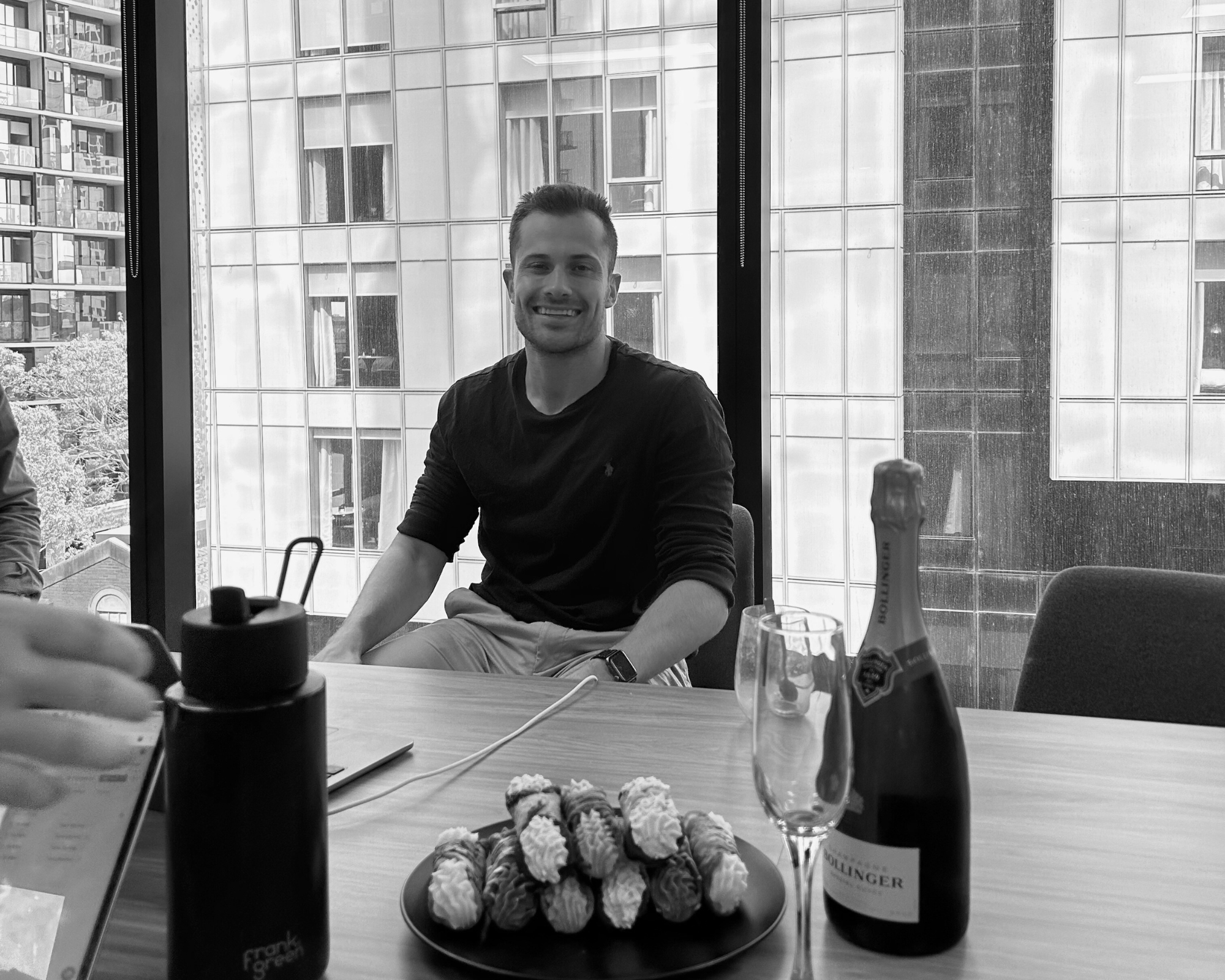 House of Psalm team member celebrating at office table with champagne and desserts for celebration