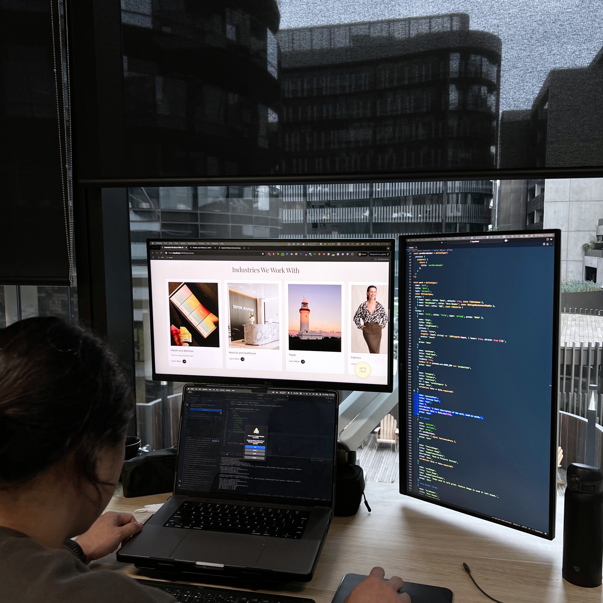 House of Psalm developer working on website code and design across dual monitors showing Reflections Holidays and fashion client pages