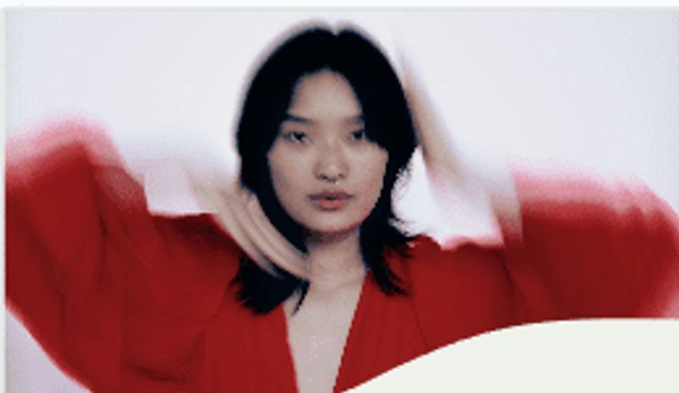 A woman in red with her arms raised, blurred in motion