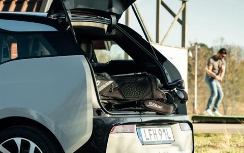 BMW i3 på golfbanen forran en mann som svinger en golfkølle. Golfbaggen ligger i bagasjerommet på BMW i3´en.