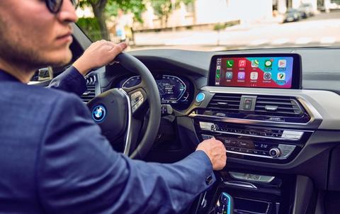 Mann i BMW ix3 med Apple Carplay i bruk