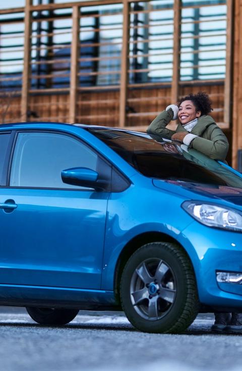 Kvinne som lener seg på en blå Citigo-e iV