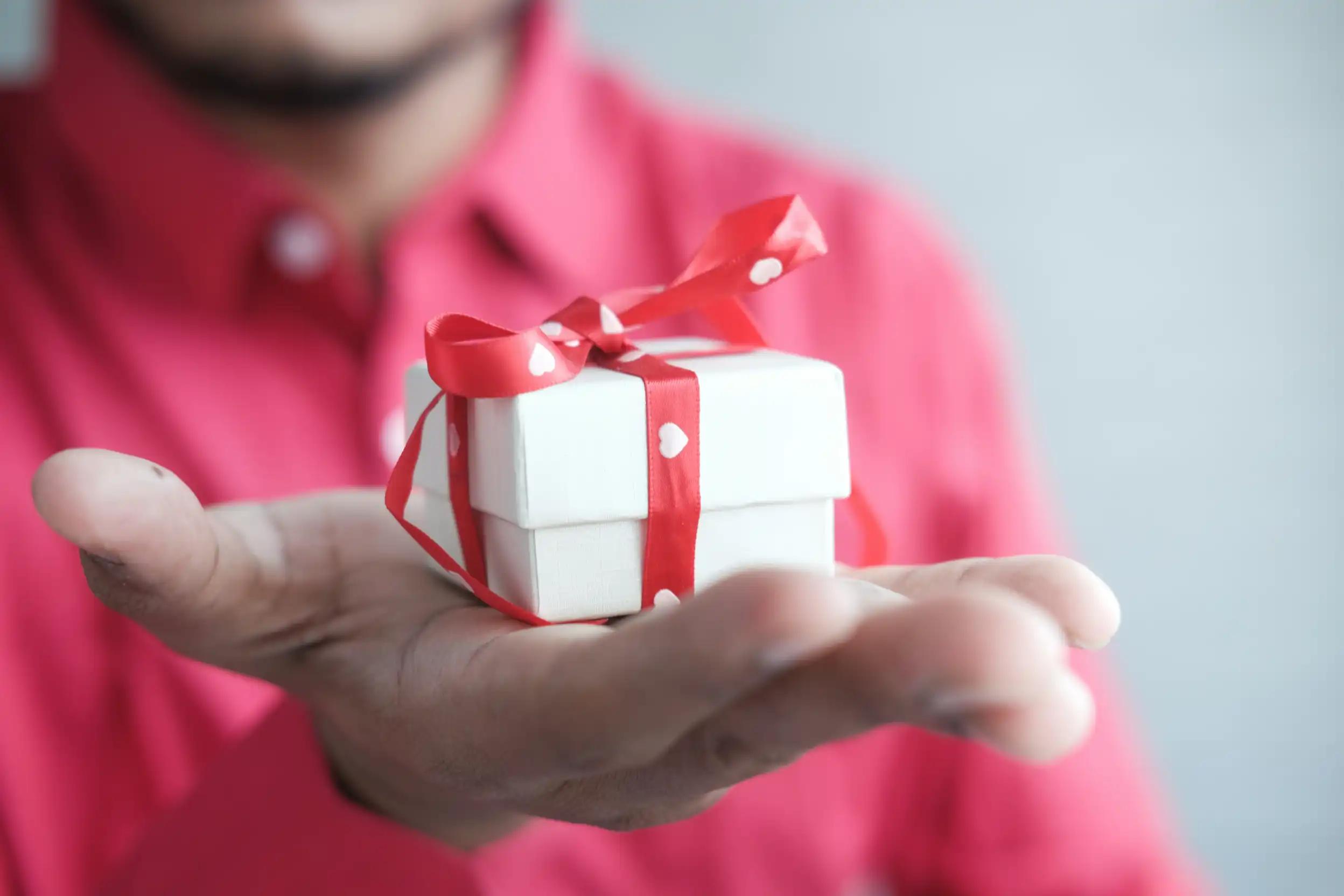 Persoon houdt een klein ingepakt cadeau vast, als illustratie van relatiegeschenken in account-based marketing.