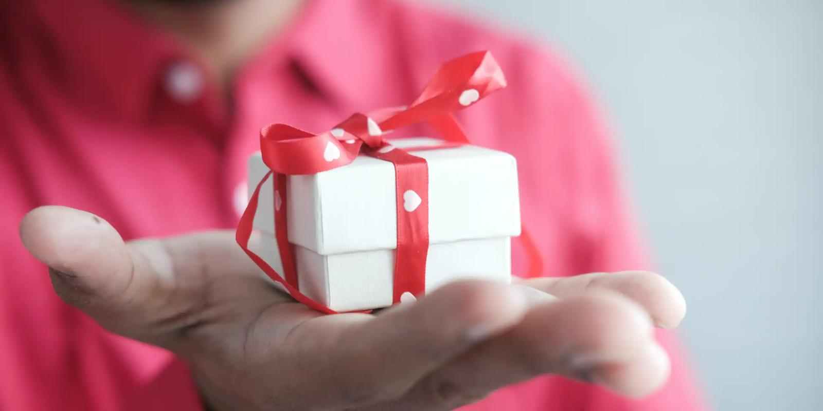 Persoon houdt een klein ingepakt cadeau vast, als illustratie van relatiegeschenken in account-based marketing.