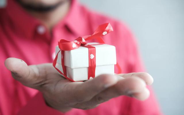 Person holding a small wrapped gift, illustrating corporate gifting for account-based marketing.