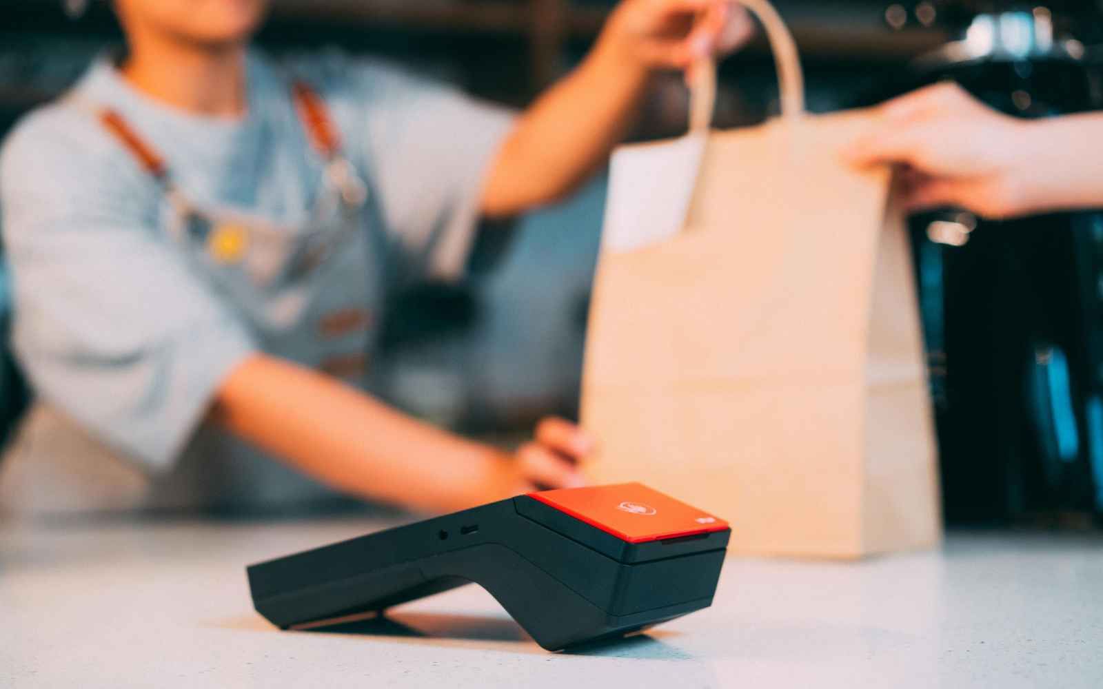 Customer receiving a shopping bag at checkout, illustrating how seasonal postcard marketing can reconnect online businesses with past customers and encourage repeat purchases