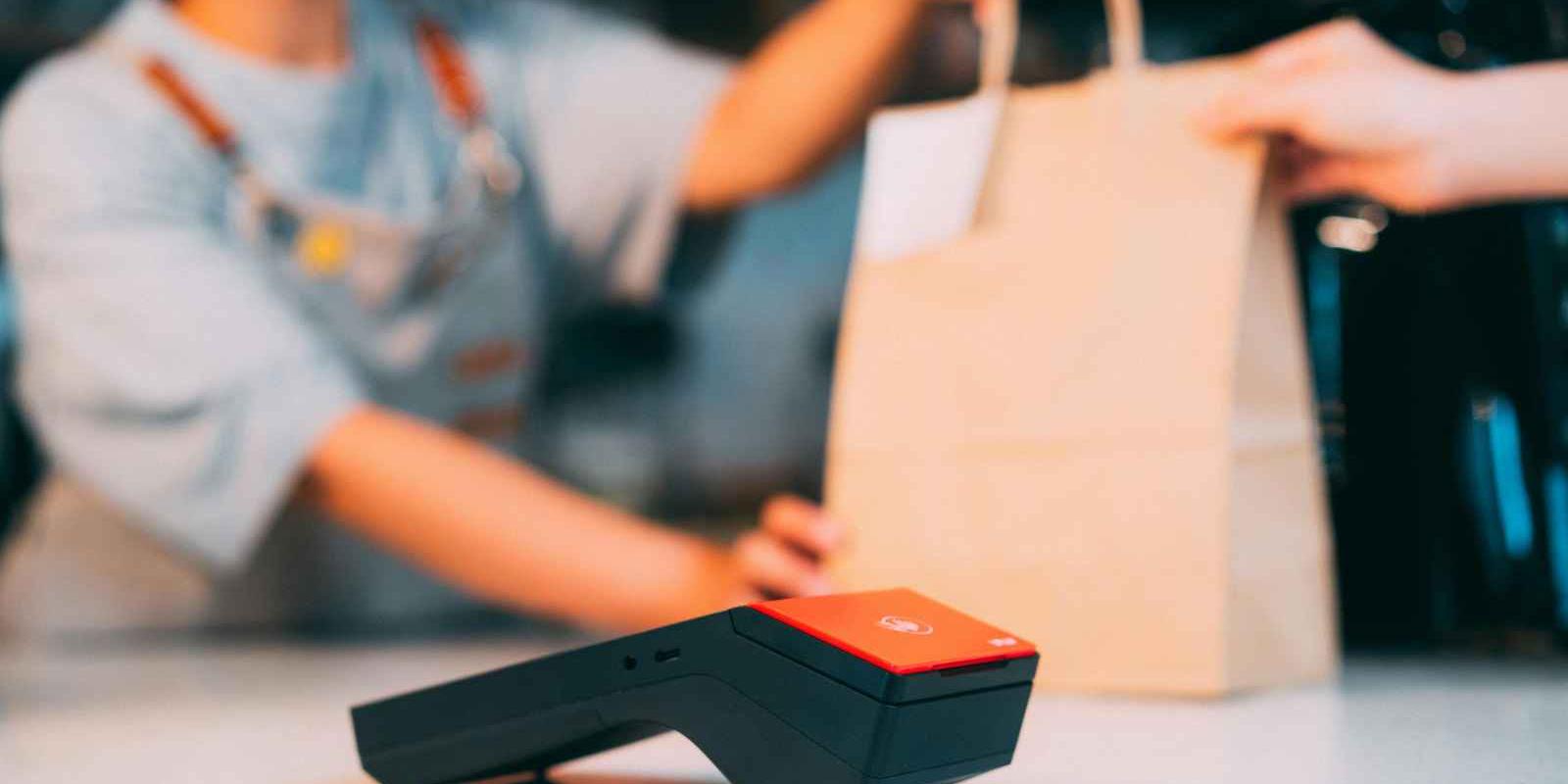 Customer receiving a shopping bag at checkout, illustrating how seasonal postcard marketing can reconnect online businesses with past customers and encourage repeat purchases