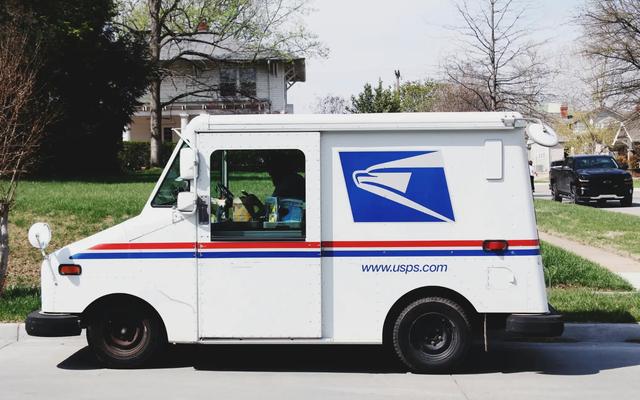 Postal delivery truck on a residential street, illustrating delivery for targeted direct mail and mass mailing.