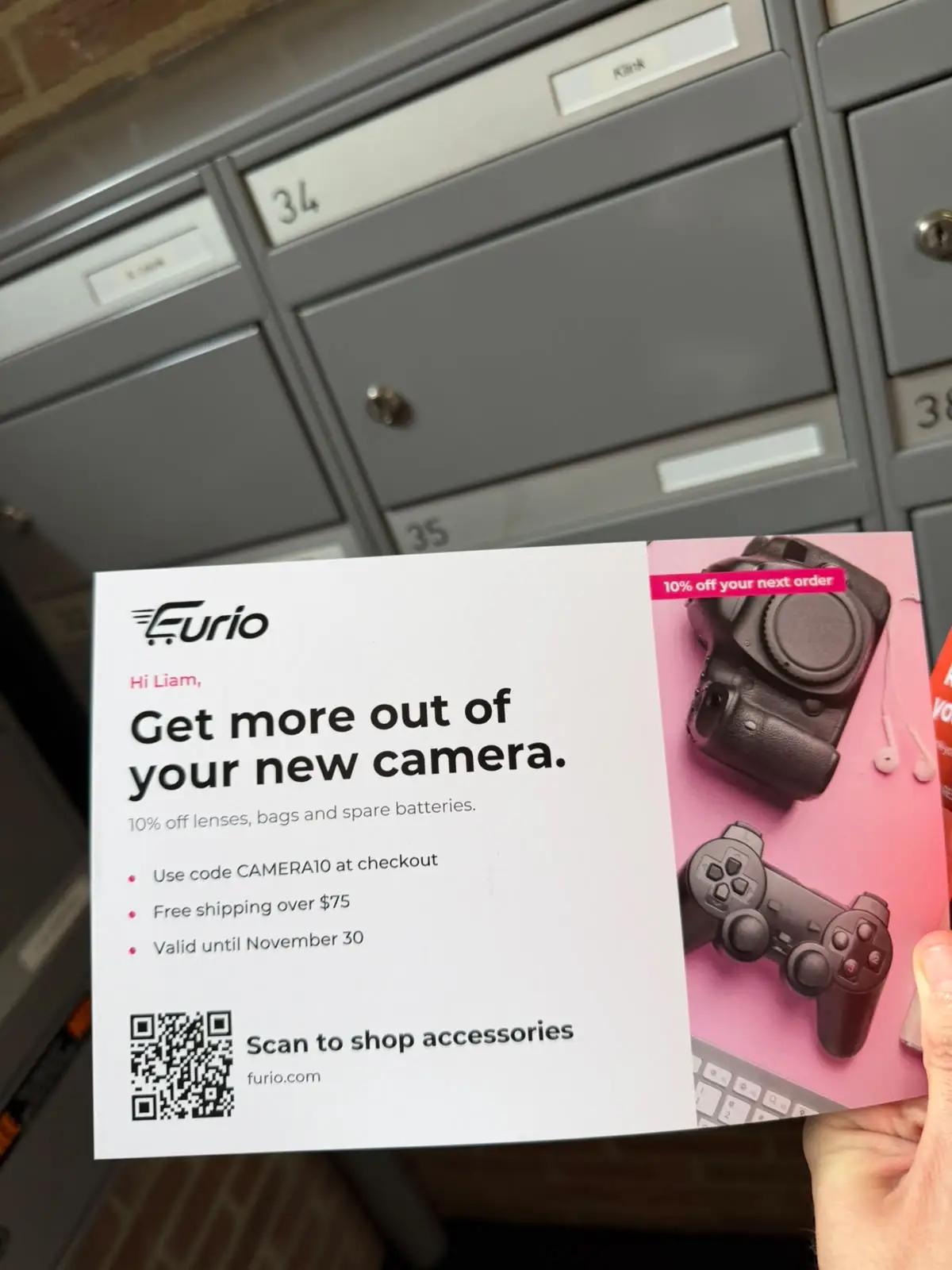 Postcard with a QR code held up in front of a wall of numbered mailboxes, each one a separate mailing address