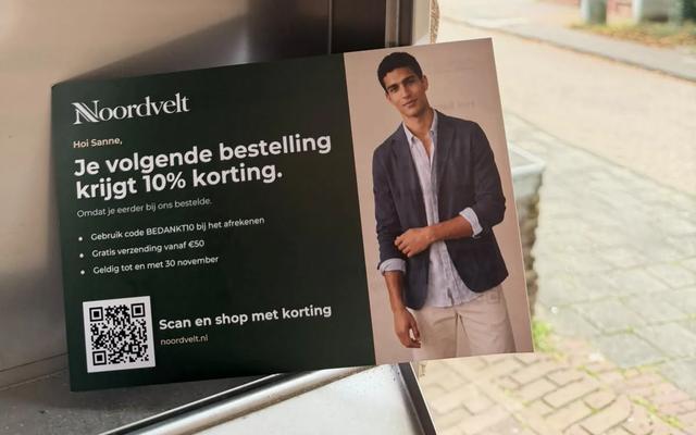 Persoonlijke kaart van een webwinkel met kortingscode en QR-code bij een Nederlandse brievenbus