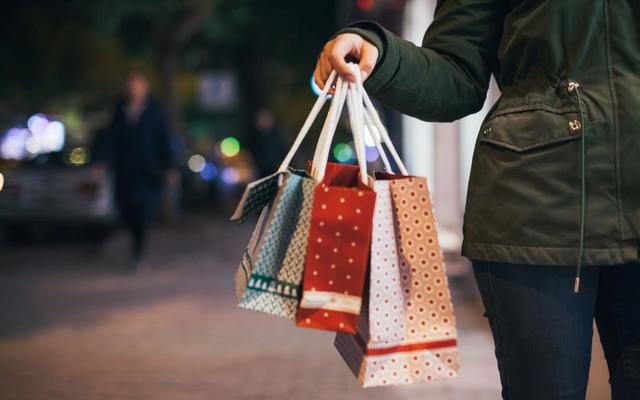 Customer receiving a shopping bag at checkout, illustrating how WooCommerce stores can encourage repeat purchases through personalized postcard marketing.
