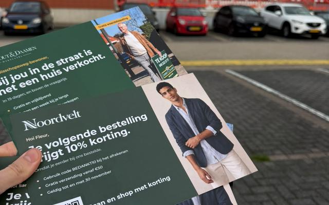 Hand holding a batch of printed postcards with QR codes outside a postal distribution centre