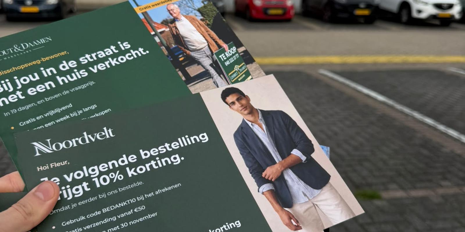 Hand holding a batch of printed postcards with QR codes outside a postal distribution centre