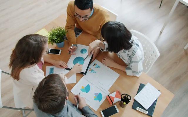 Overhead view of a team around a table reviewing campaign charts and printed reports