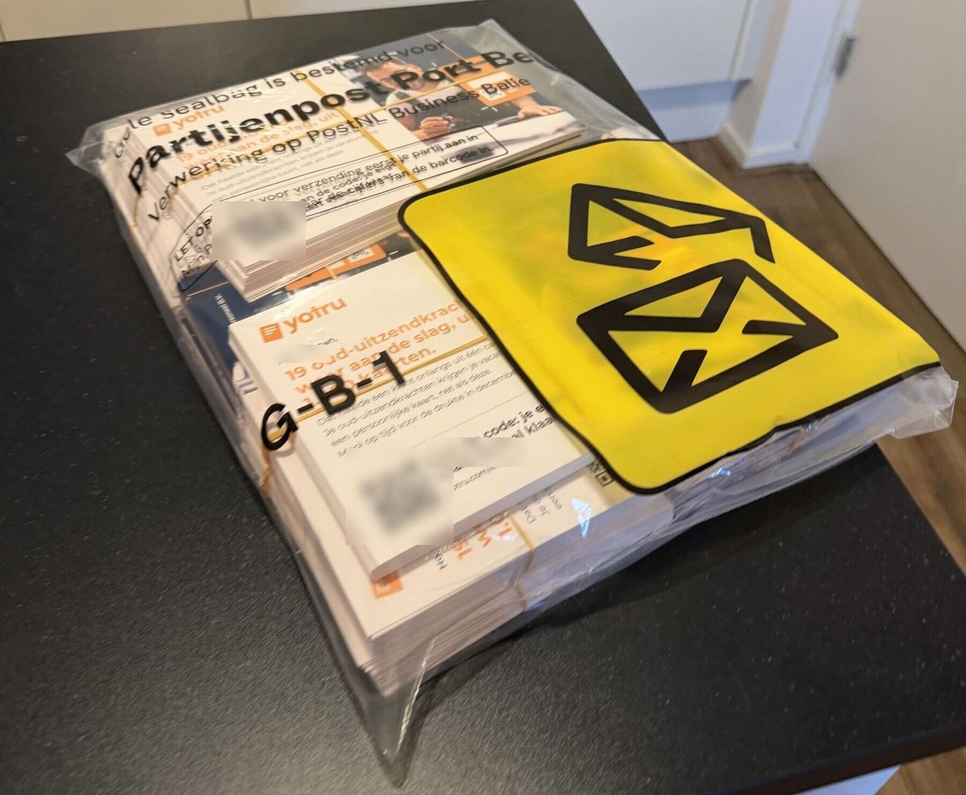 Doorzichtige sealbag vol persoonlijke Yotru-kaarten, met een PostNL-partijenpostformulier en een gele PostNL-sticker