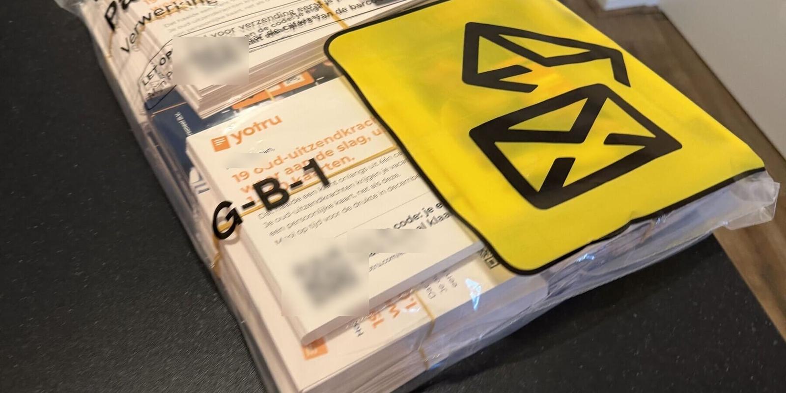 Doorzichtige sealbag vol geadresseerde ansichtkaarten met een PostNL-partijenpostformulier en een gele PostNL-sticker, klaar om aan te leveren